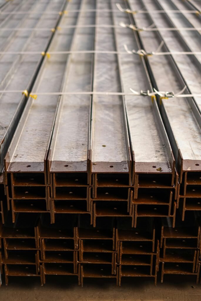 Close-up of neatly stacked steel beams in a warehouse, showcasing metal texture and industrial symmetry.