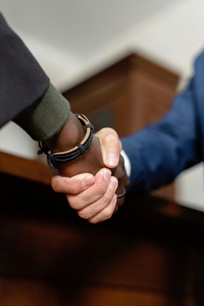 Two professionals shaking hands in an indoor setting, symbolizing agreement and partnership.